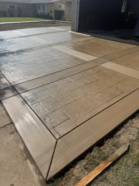 Stamped concrete slab driveway with decorative stone pattern and smooth borders at residential home